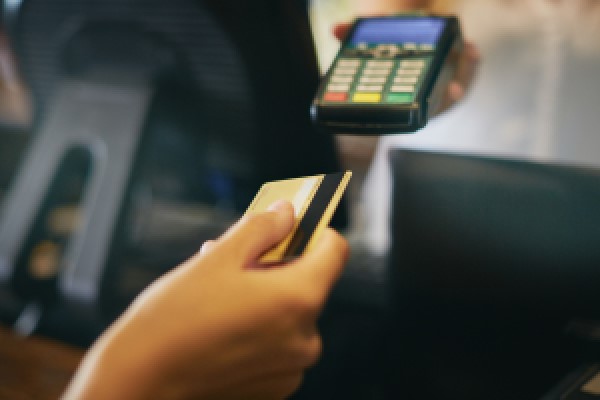 Hand holding a credit card about to be inserted into a retail POS device.