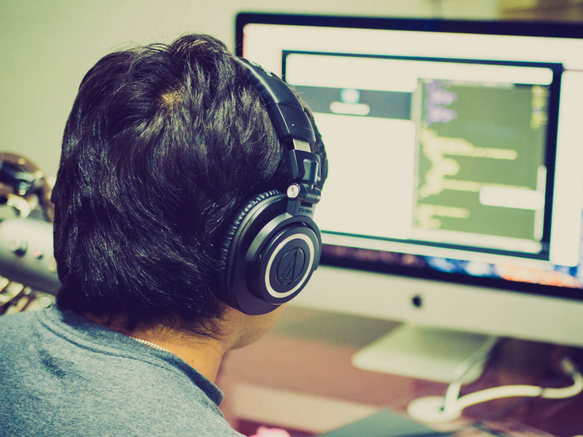 Man wearing headphones, working on a computer.