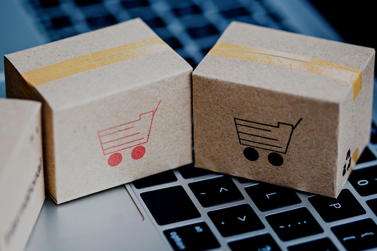 Miniature boxes with shopping cart icons sitting atop a laptop keyboard.