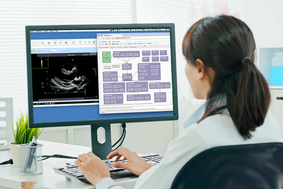 Female in lab coat sitting at a computer, using Eggplant to test open EMR.