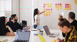 Woman standing in conference room, looking at post-its arranged on the wall.