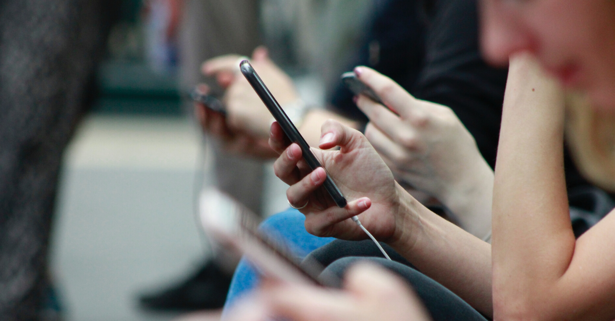 Side view of a row of hands, holding mobile phones.